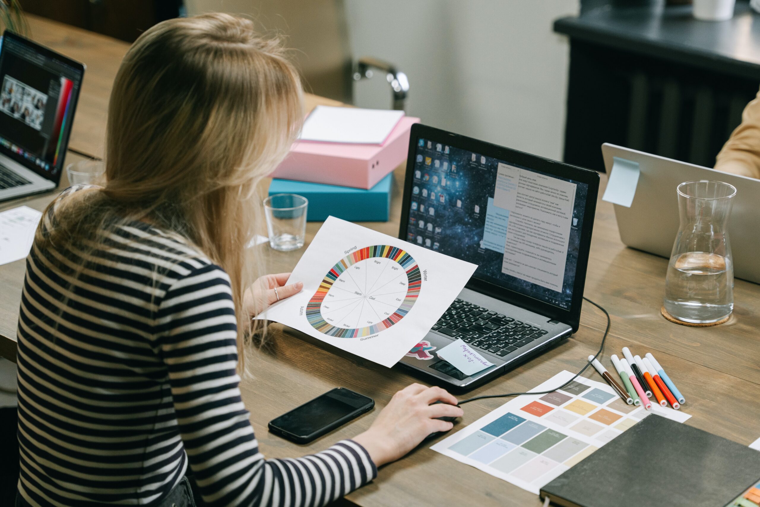 Woman looking at a color wheel while using a laptop