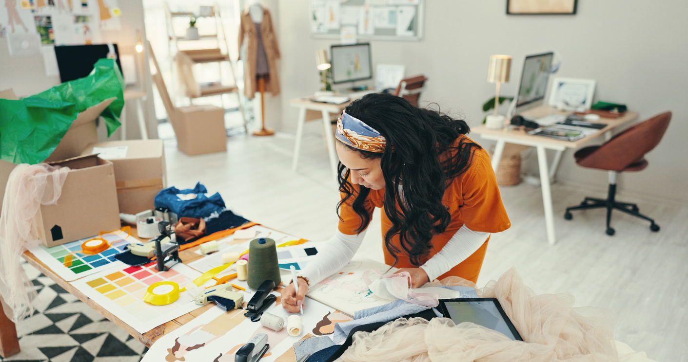 Fashion designer, woman and sketch at desk for planning clothing design and choosing fabric for product sample