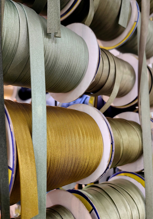 Coils bias tape in various colors are neatly organized on racks in textile processing workshop, showcasing vibrant options available for crafting and sewing. close up