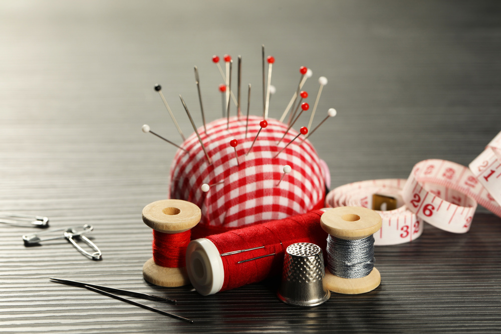 Different sewing tools on wooden table, closeup