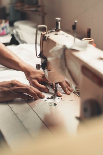 Person stitching a piece of fabric by using a sewing machine