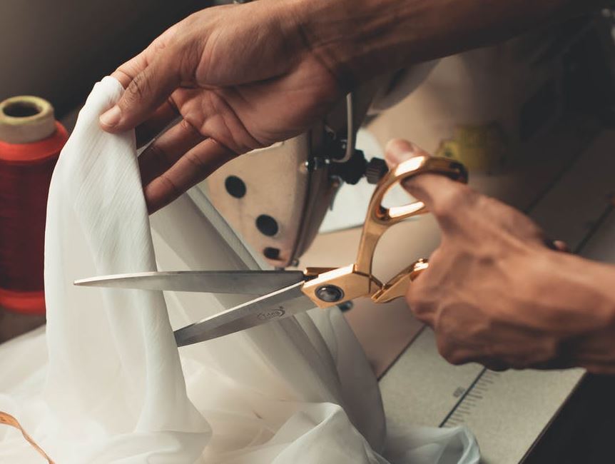 person cutting through a white cloth with scissors