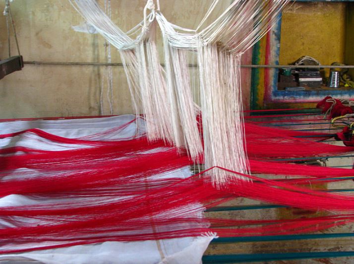 silk threads on a hand-loom being woven into a fancy sari