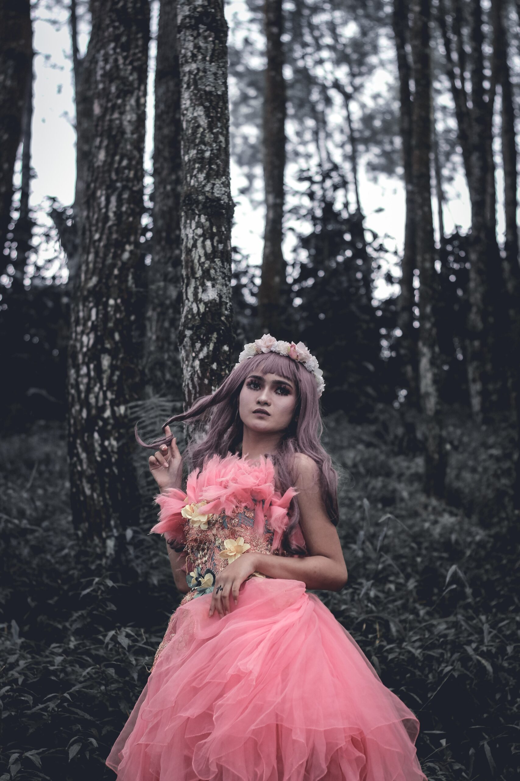 Emotionless woman in pink evening dress standing in summer forest